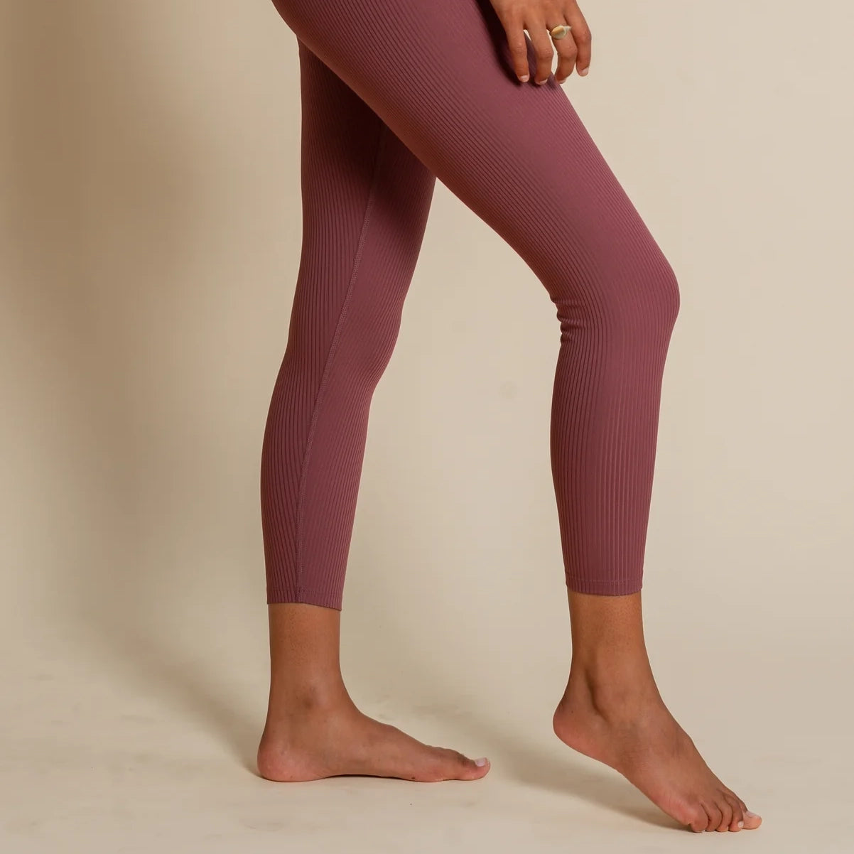 A pair of legs wearing burgundy Girlfriend Collective leggings.