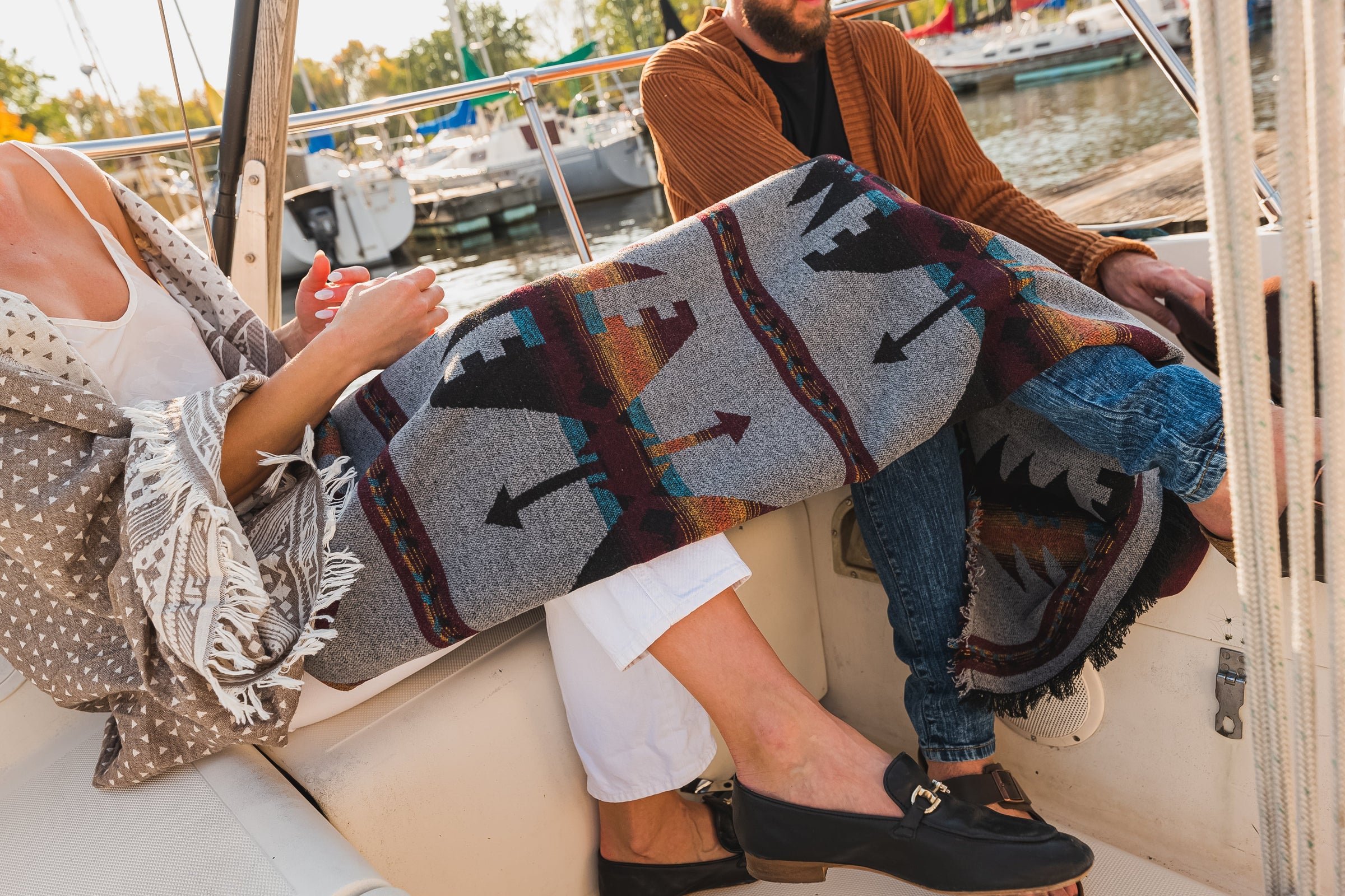 A man and a woman on a boat with a blanket draped over their legs.