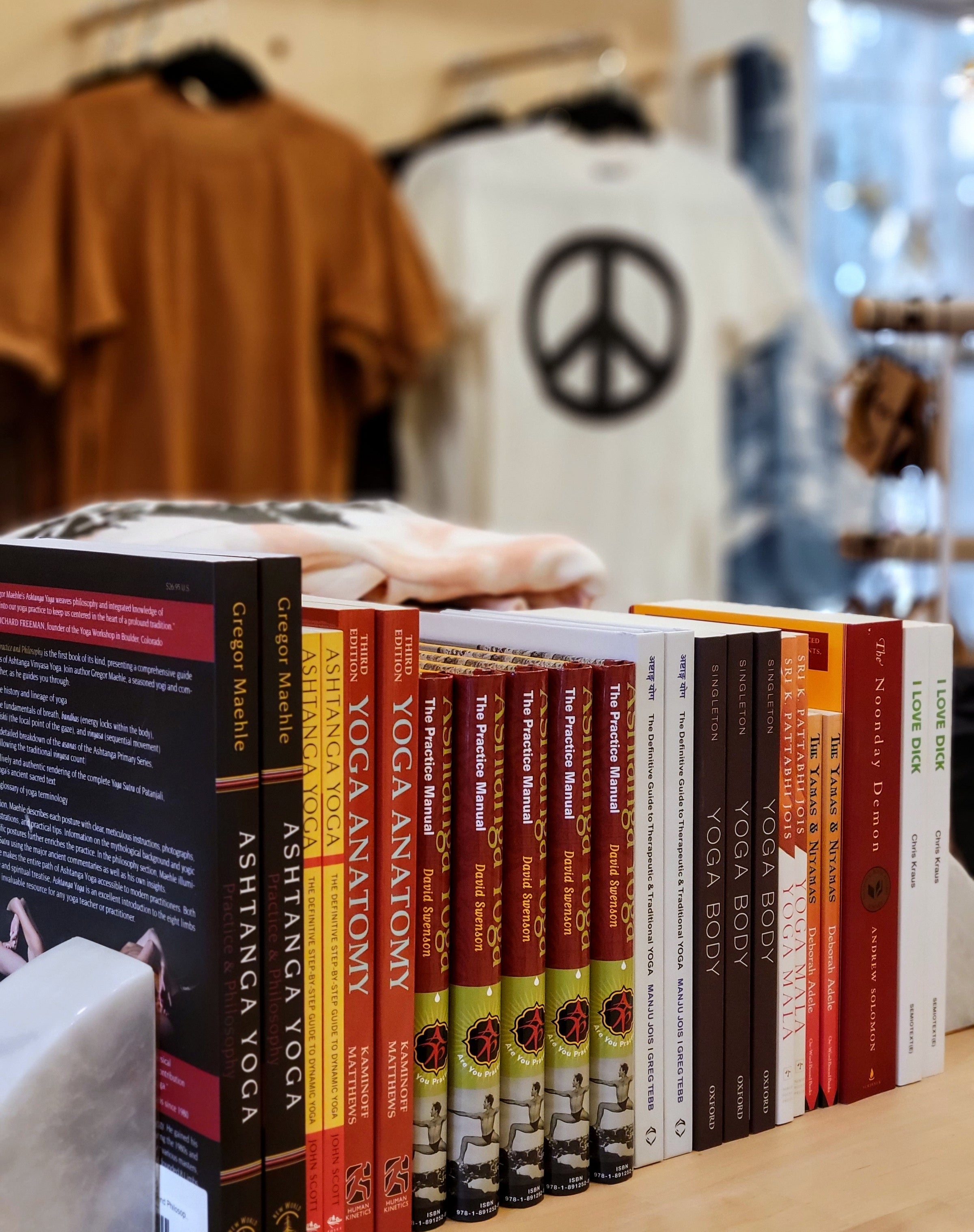 Yoga books on a shelf in front of a rack of t-shirts.