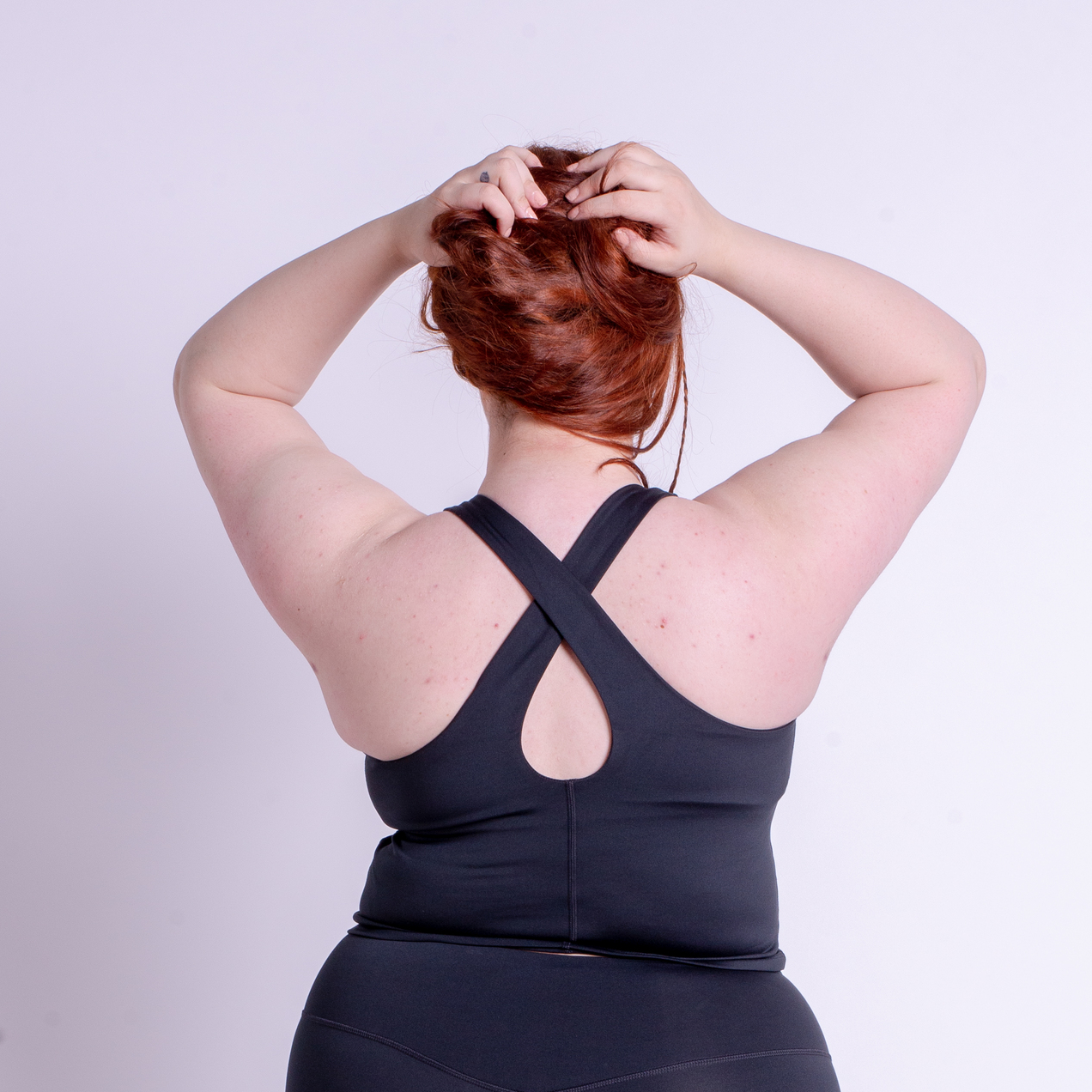 A woman wearing a black Girlfriend Collective tank from the back.