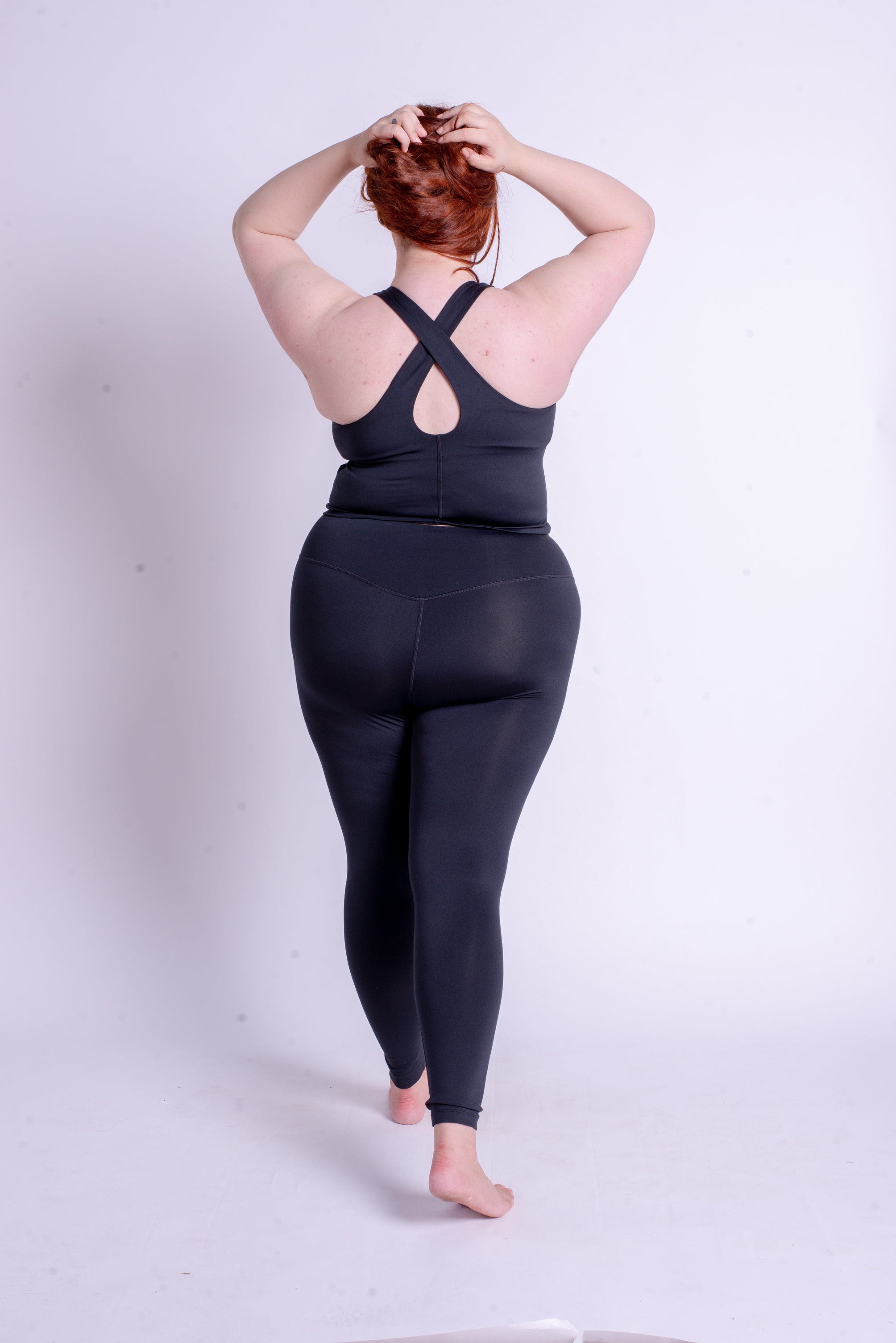 A woman wearing black Girlfriend Collective tank and leggings.